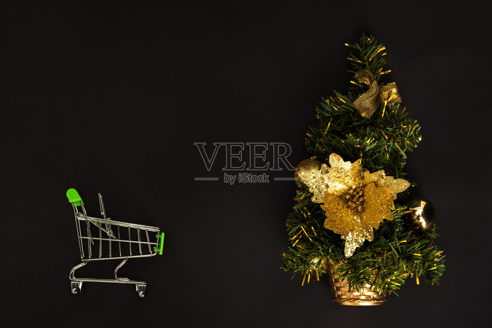 圣诞树上的黑色背景和购物车视图在顶部。买礼物的概念。照片摄影图片