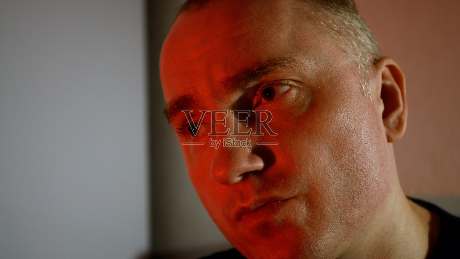 一个神情严肃的年轻人。眉头紧锁,红调邪恶微笑的男人照片摄影图片