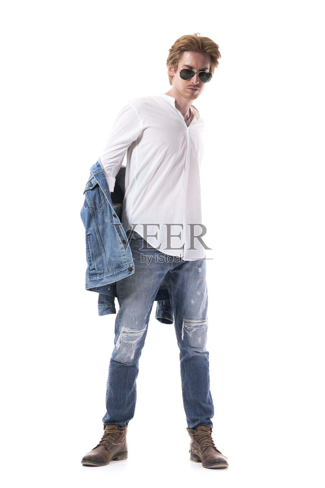 酷时尚的年轻人脱下了牛仔裤夹克向下看。照片摄影图片