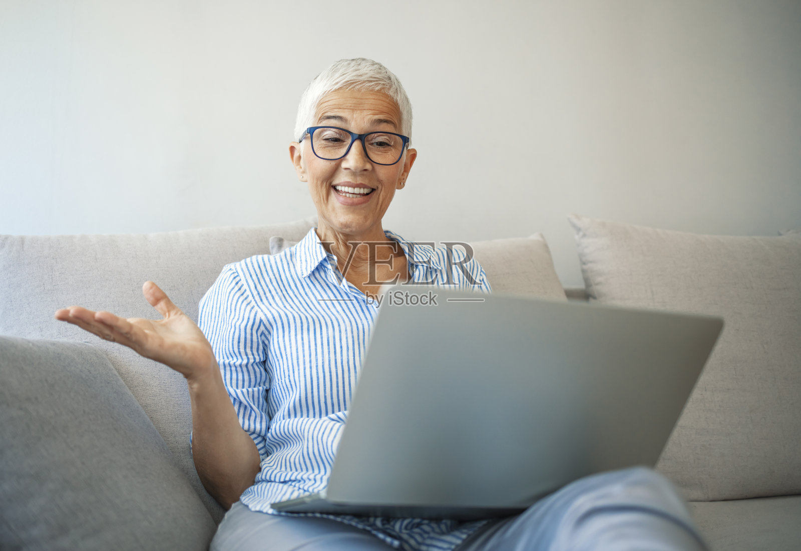 满头白发,笑容满面的老妇人在家用笔记本电脑照片摄影图片