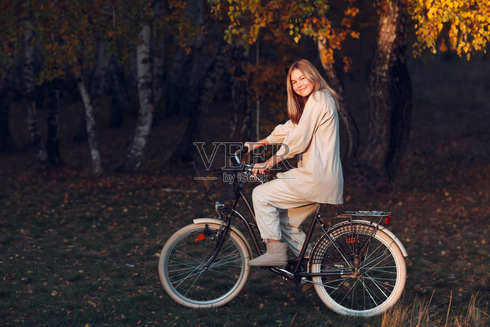 快乐活跃的年轻女子在秋天的公园骑自行车照片摄影图片