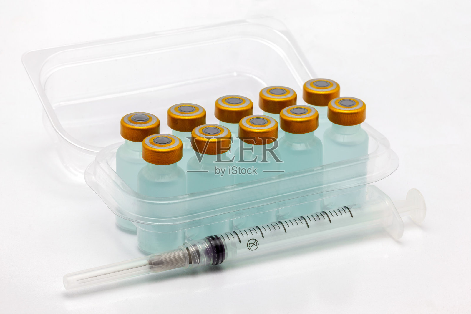 十个疫苗瓶装在打开的半透明塑料盒里和一个注射器照片摄影图片