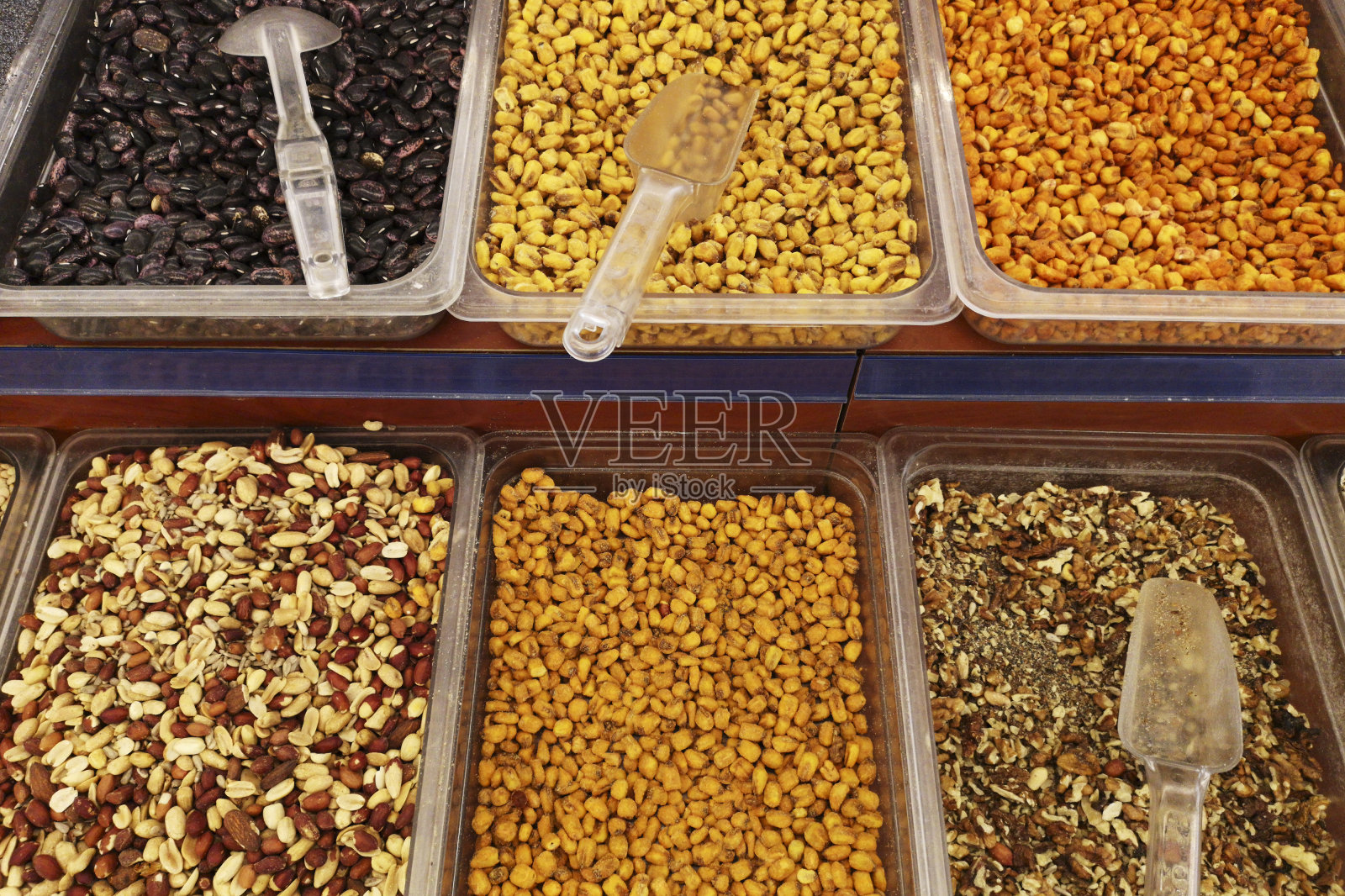 很多分门别类的干果和坚果,开心果,花生,李子,方形餐具。市场上各种干果和坚果照片摄影图片