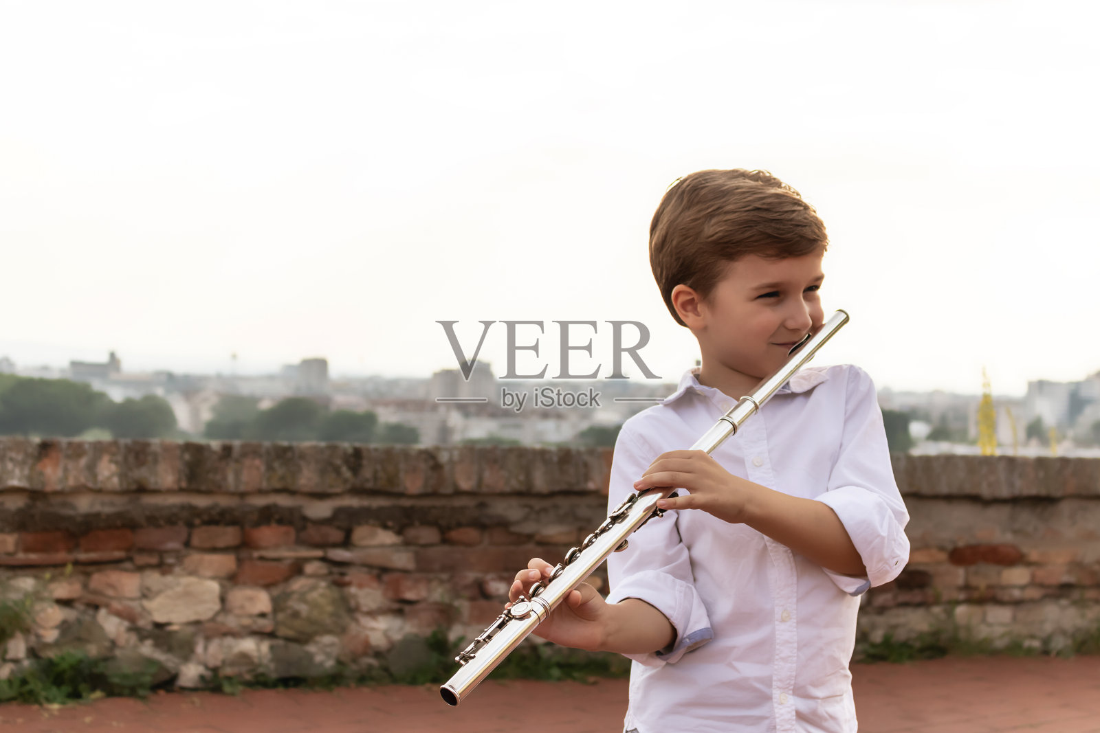 快乐的孩子吹笛子。照片摄影图片