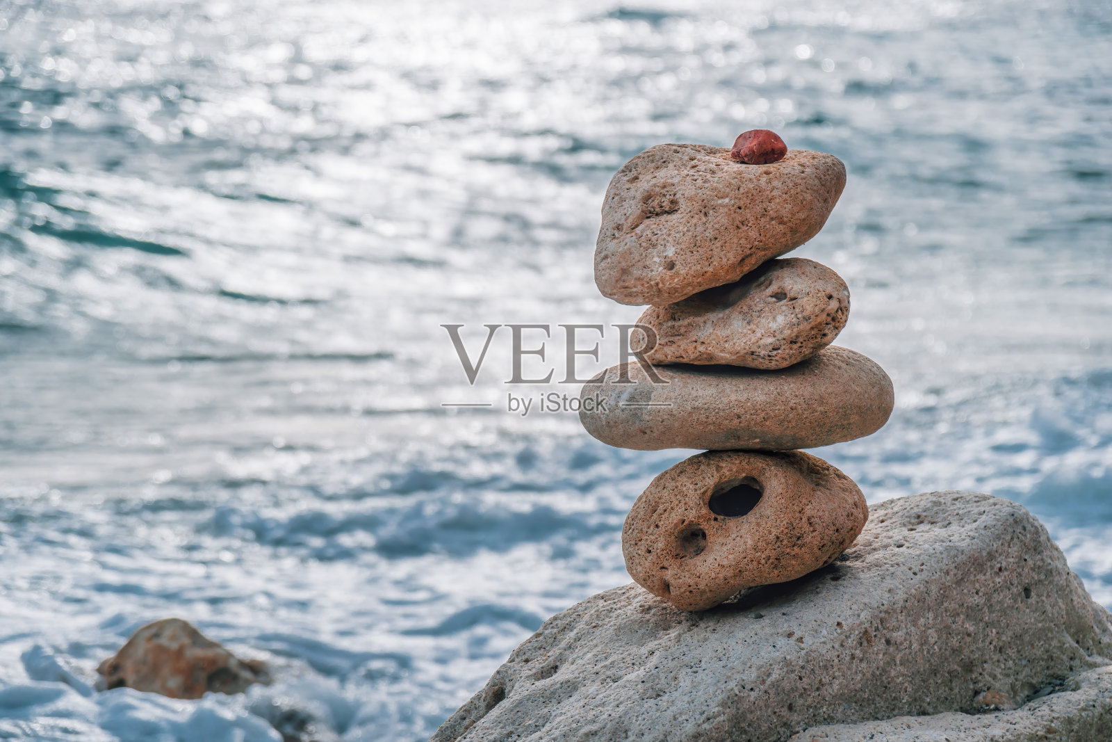 在一个阳光明媚的日子,平衡的卵石金字塔在海滩上。背景是大海的泡沫。有选择性的重点。海滩上的禅石,冥想,水疗,和谐,平静,平衡的概念照片摄影图片