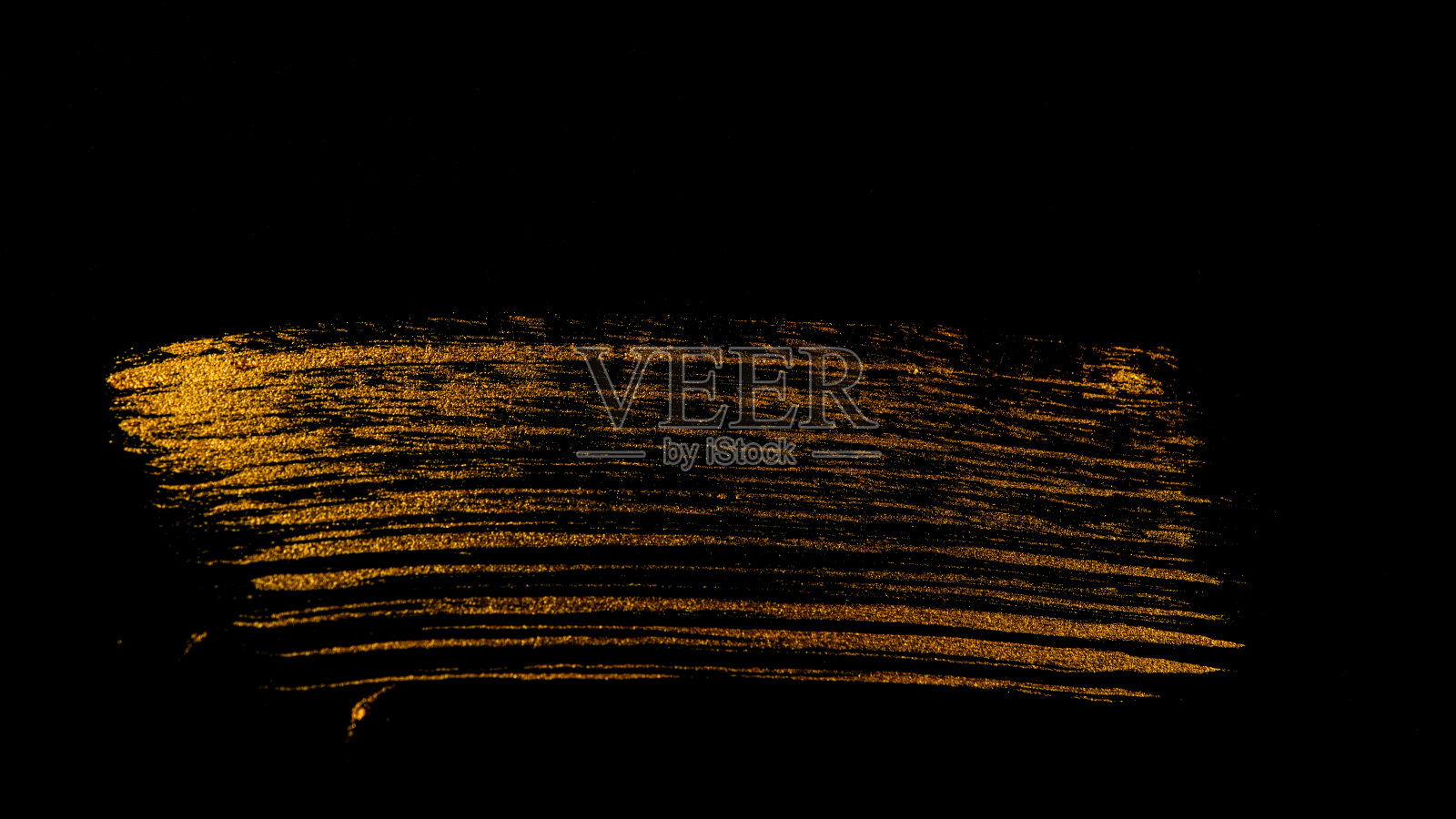 用画笔在黑色的背景上画出金色的痕迹。照片摄影图片