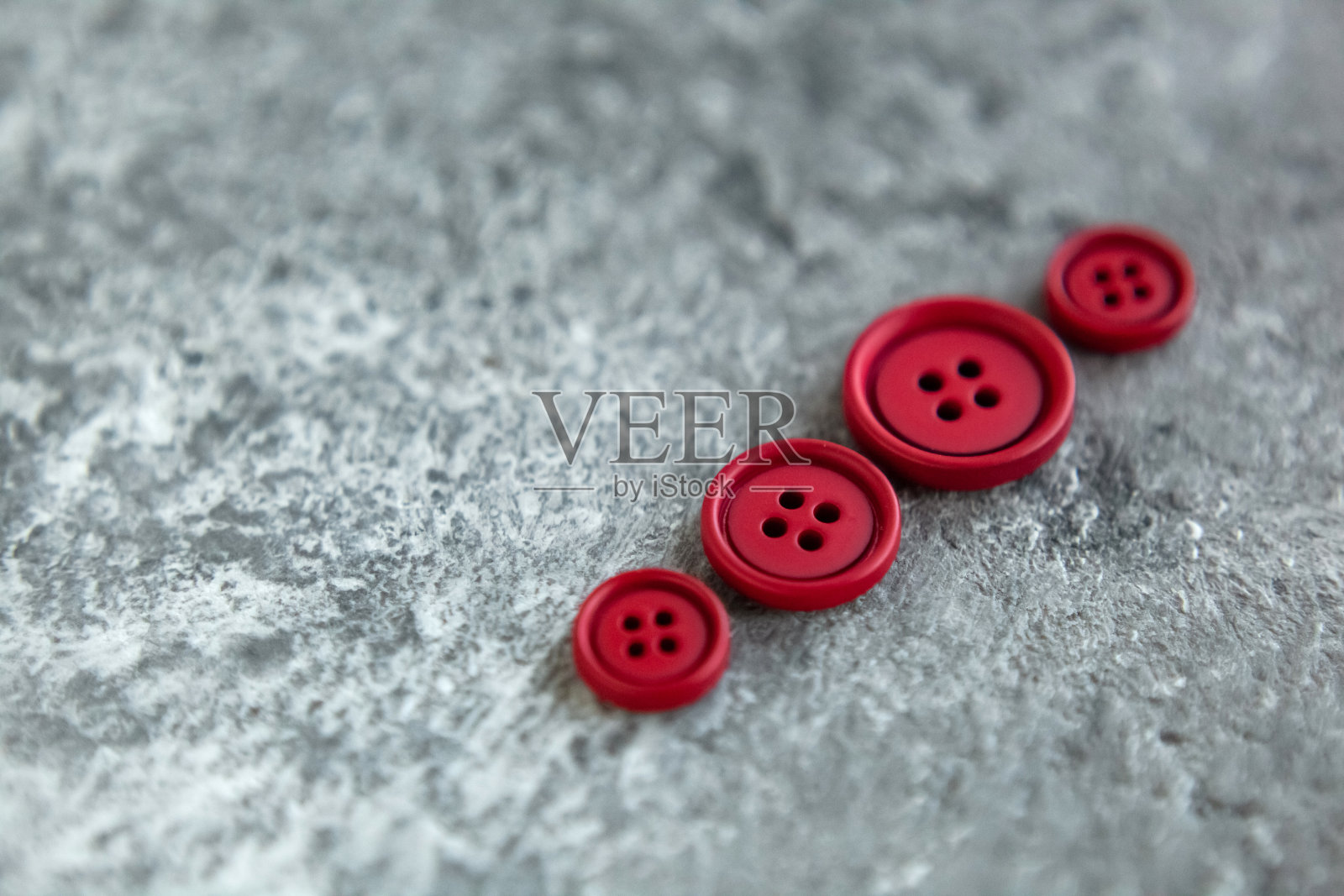 在混凝土背景上堆放磨砂按钮,微距虚化。美丽的刺绣照片摄影图片