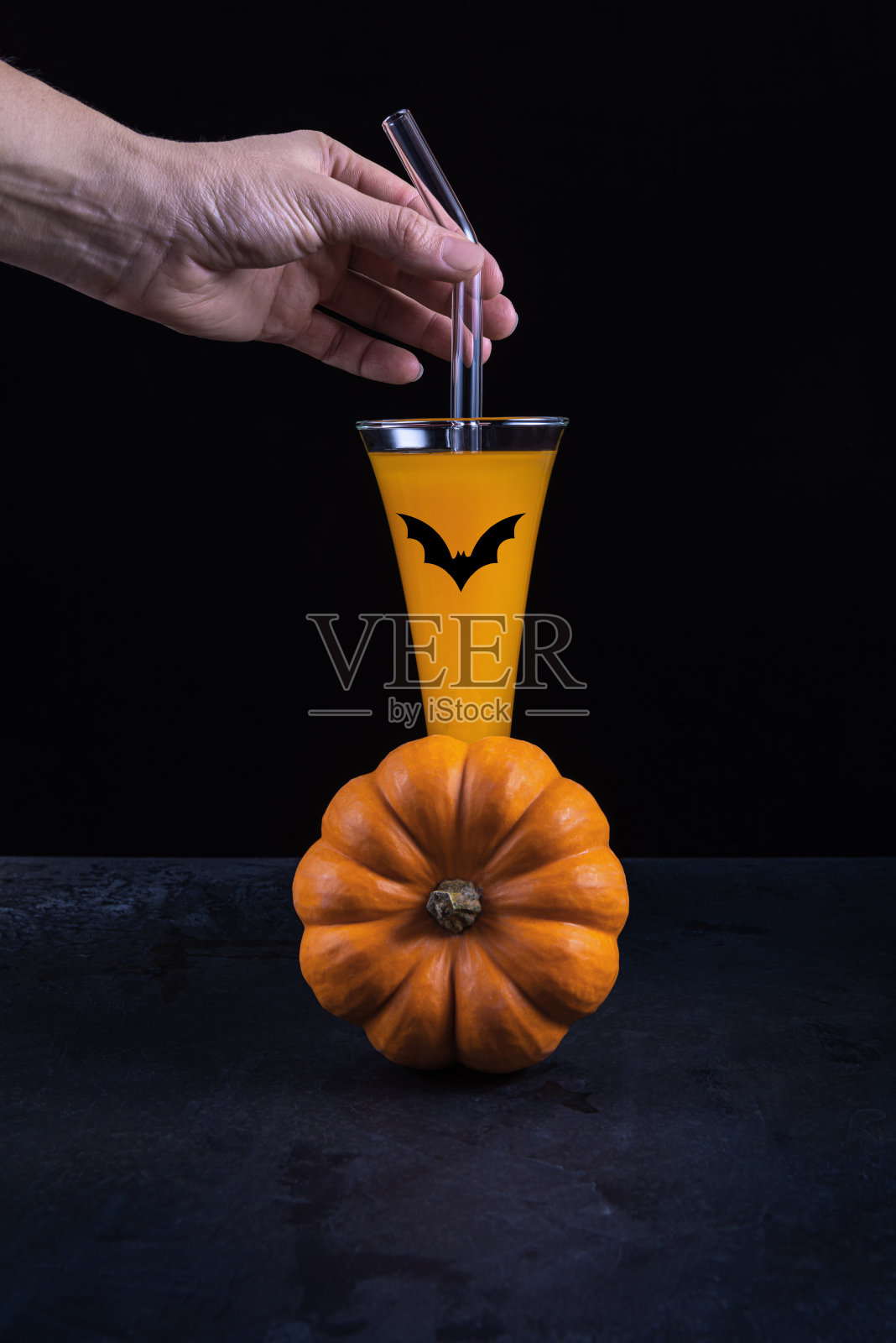 手握南瓜鸡尾酒,玻璃吸管和球棒照片摄影图片