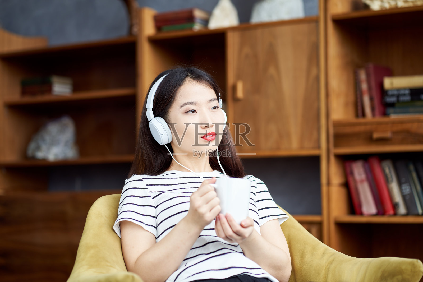 年轻美丽的亚洲女孩听音乐耳机坐在椅子上照片摄影图片