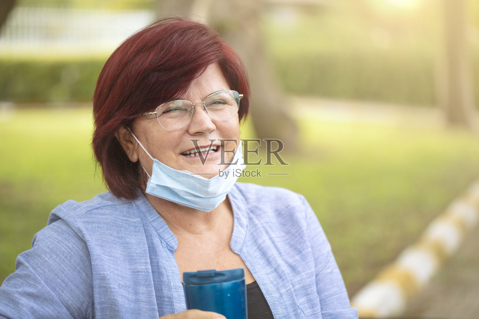 成熟的朴女士带着咖啡杯和医用口罩。照片摄影图片