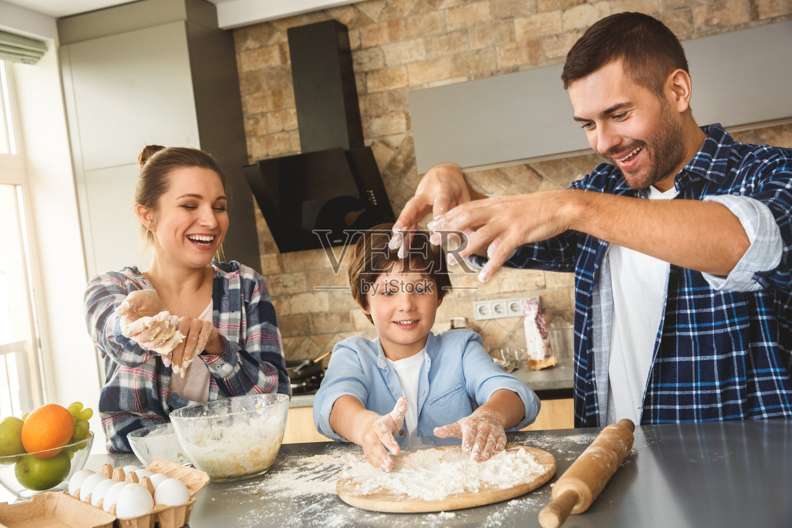一家人站在厨房的餐桌旁,一起玩着面粉,开心地笑着照片摄影图片