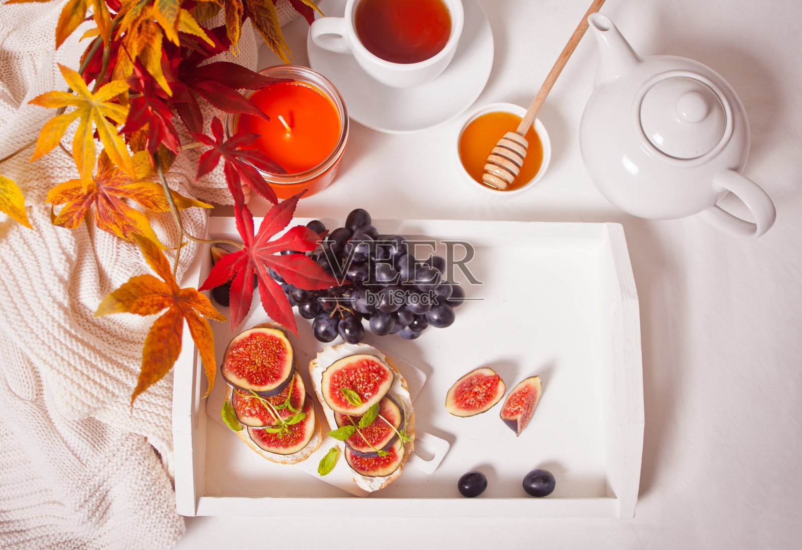 白色托盘上有奶油乳酪、无花果和蜂蜜的三明治。健康早餐食品理念。照片摄影图片