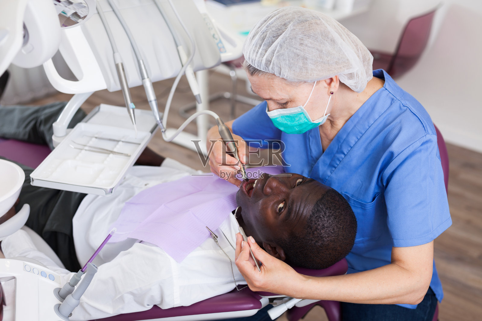 牙科医生为坐在医疗椅上的病人专业补牙照片摄影图片