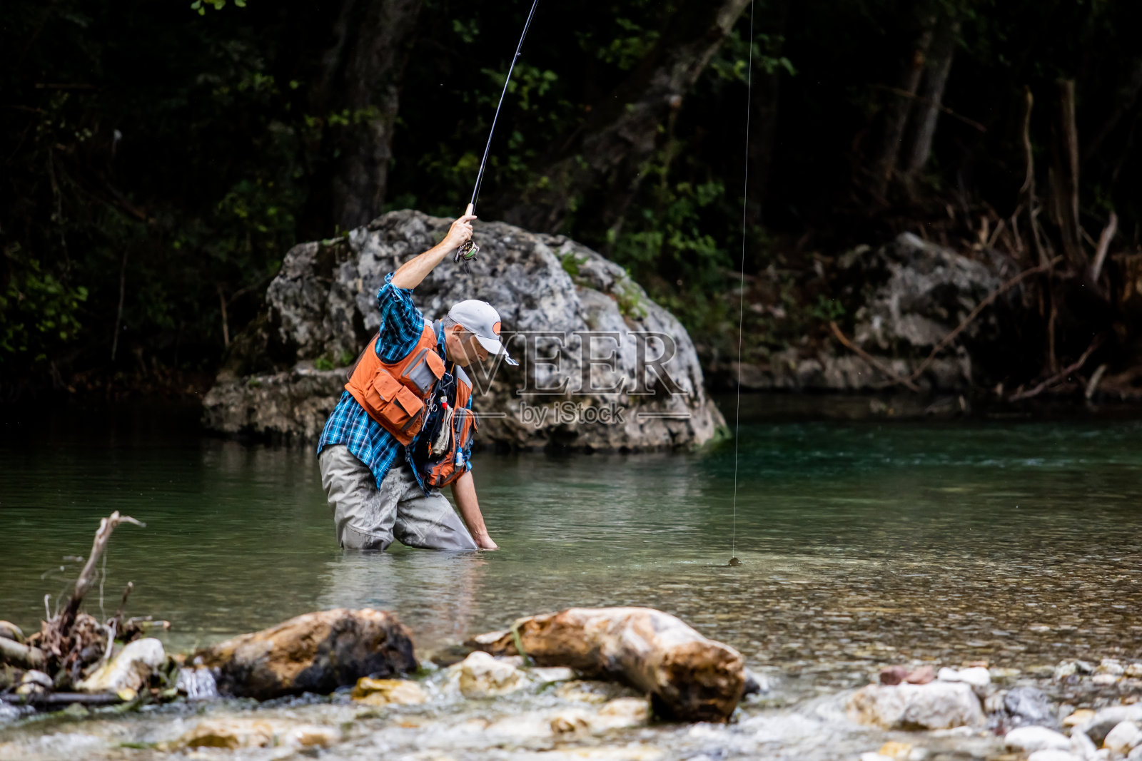 一个飞钓者在山间的河里钓鳟鱼照片摄影图片
