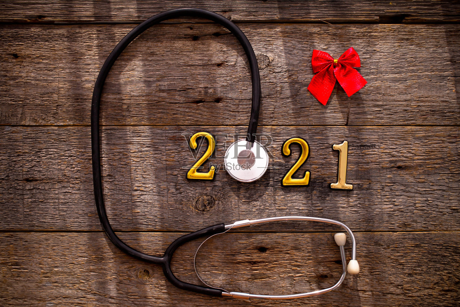 带有2020号码的听诊器和木制背景上的红色蝴蝶结。恭贺新禧,万事如意。照片摄影图片