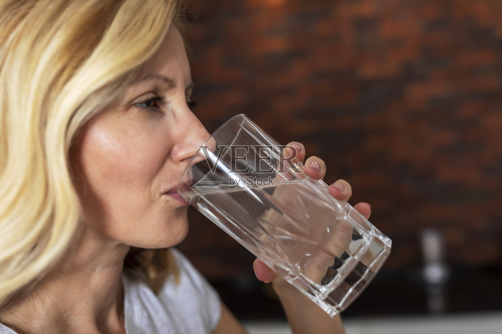 成熟的女人喝水。照片摄影图片