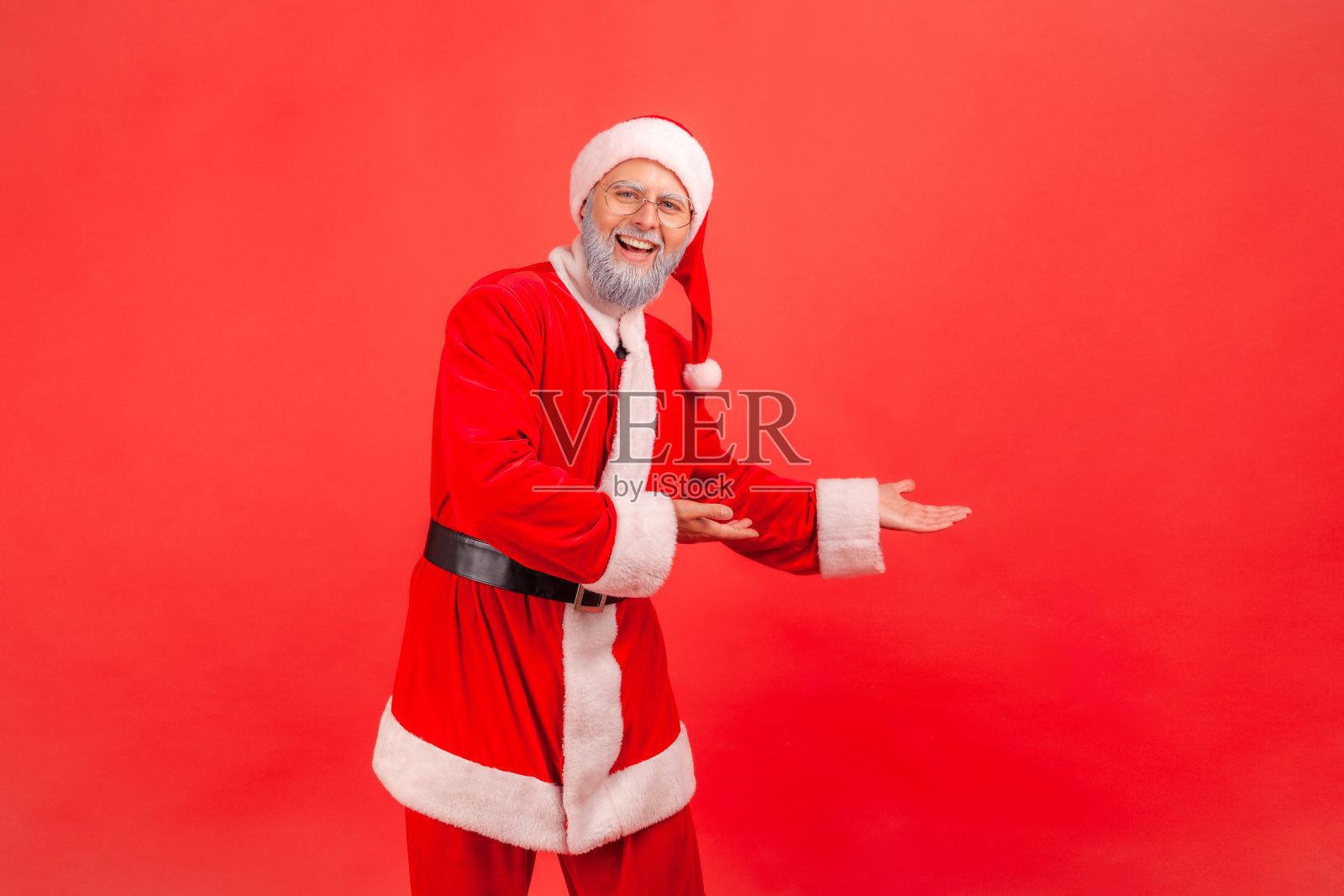 积极满意的灰色胡子圣诞老人显示空的空间,关注广告区域照片摄影图片