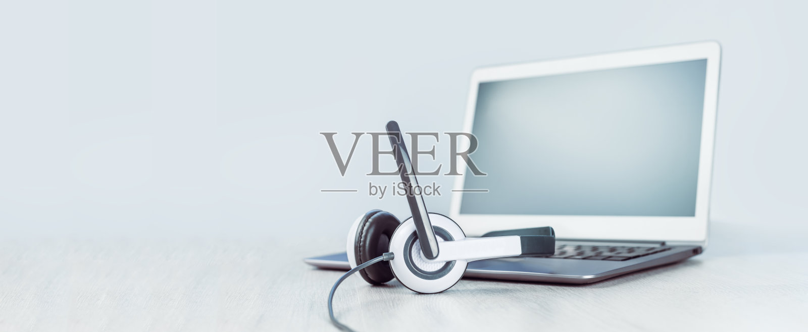 白色桌子上放着带耳机的笔记本电脑照片摄影图片