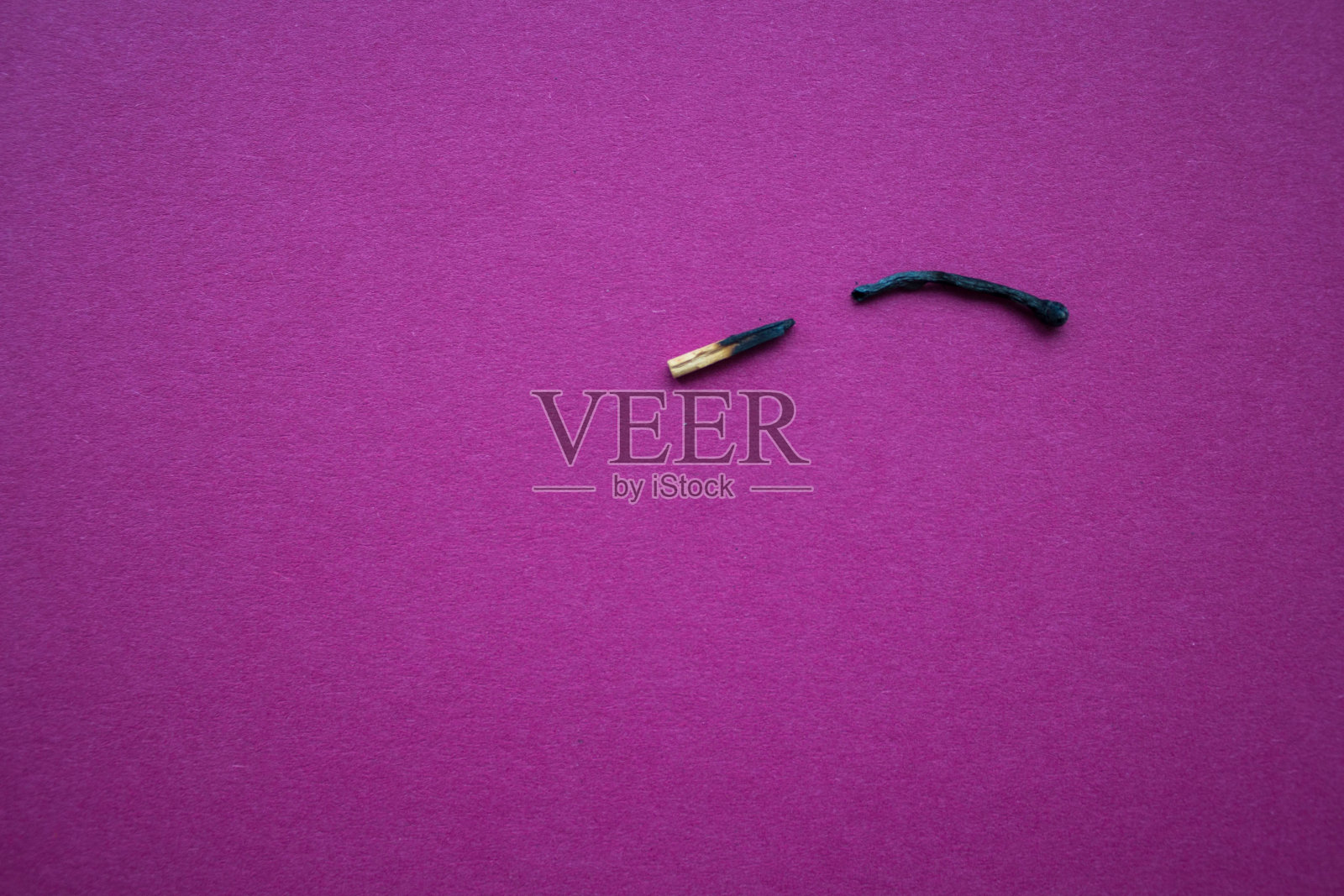 一根烧过的火柴在淡紫色的背景上断成两半照片摄影图片