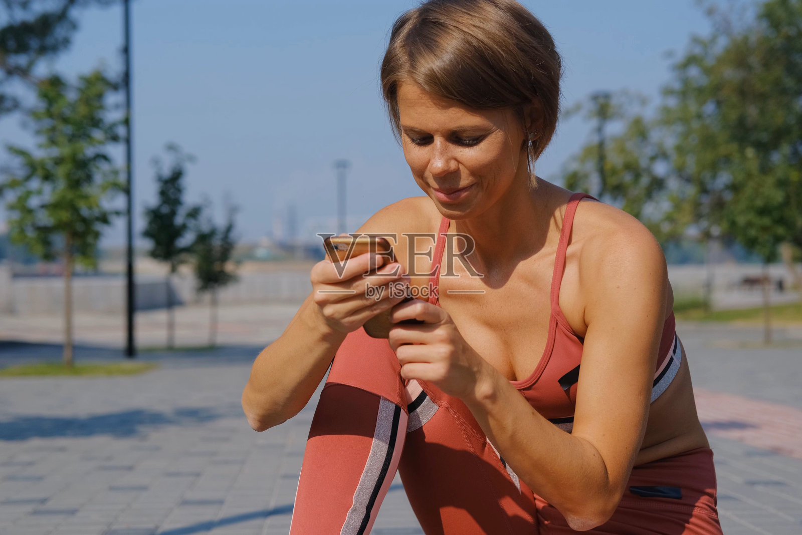 一位年轻貌美的女子用智能手机进行远距离瑜伽训练。这位运动员用这款应用计算手机里的卡路里。照片摄影图片