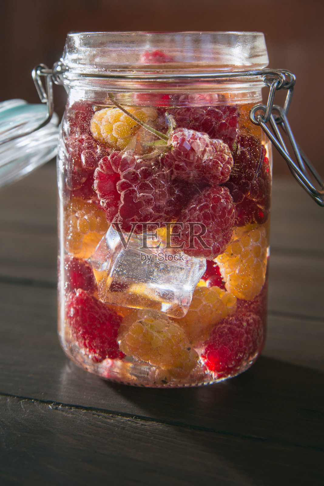 黄色和红色的覆盆子放在一个装有冰的玻璃罐里,靠近点照片摄影图片