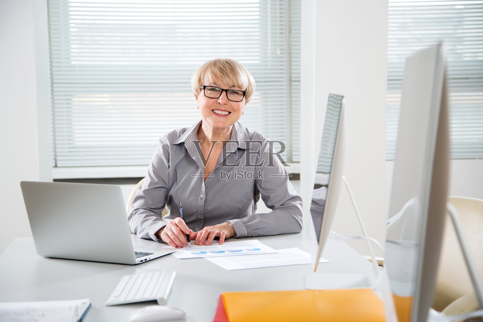 这是一个在办公室里看着照相机的成熟商业女性的肖像照片摄影图片