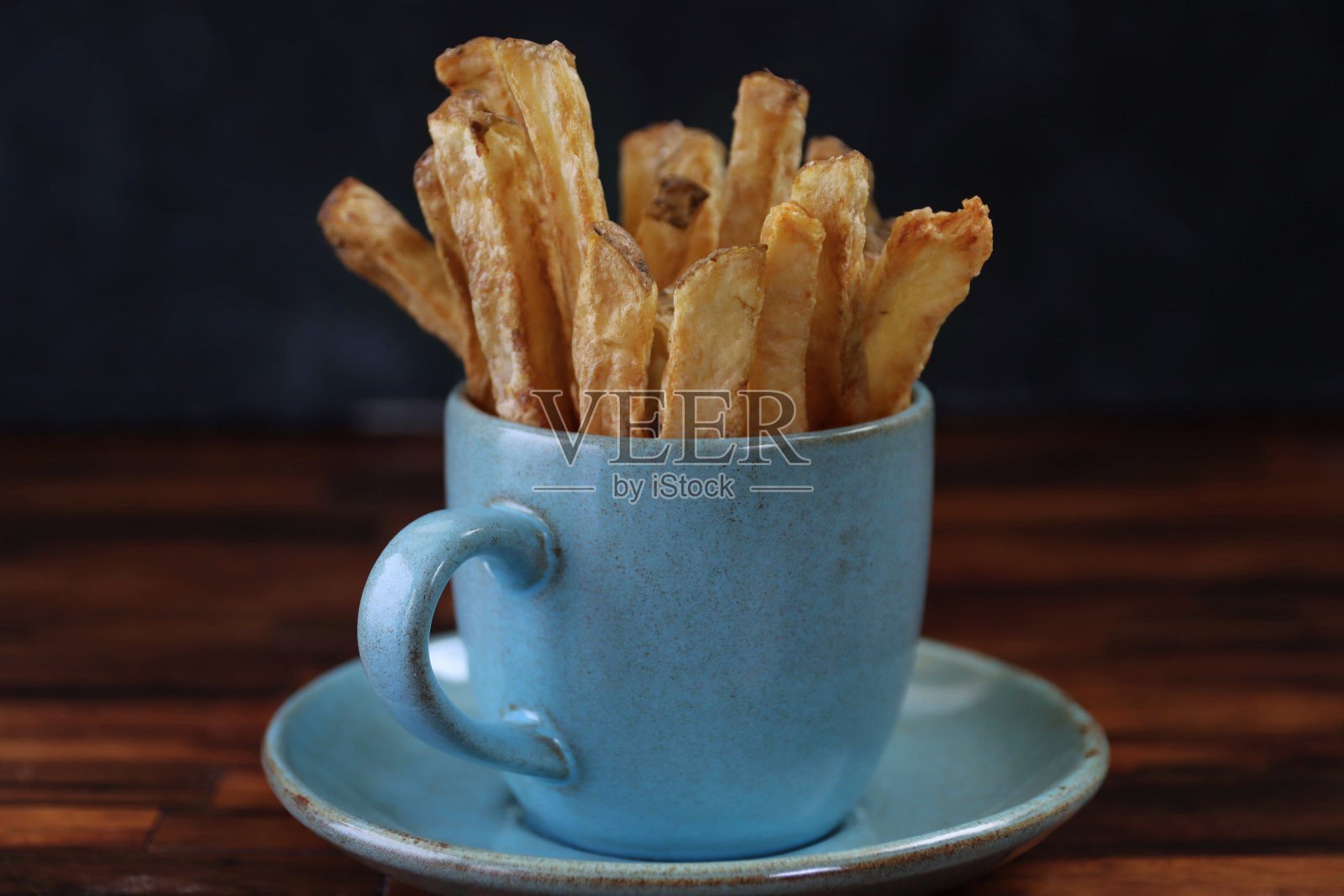 在黑暗背景下的木桌上摆放着自制的法式炸薯条,这是一张特写图片照片摄影图片