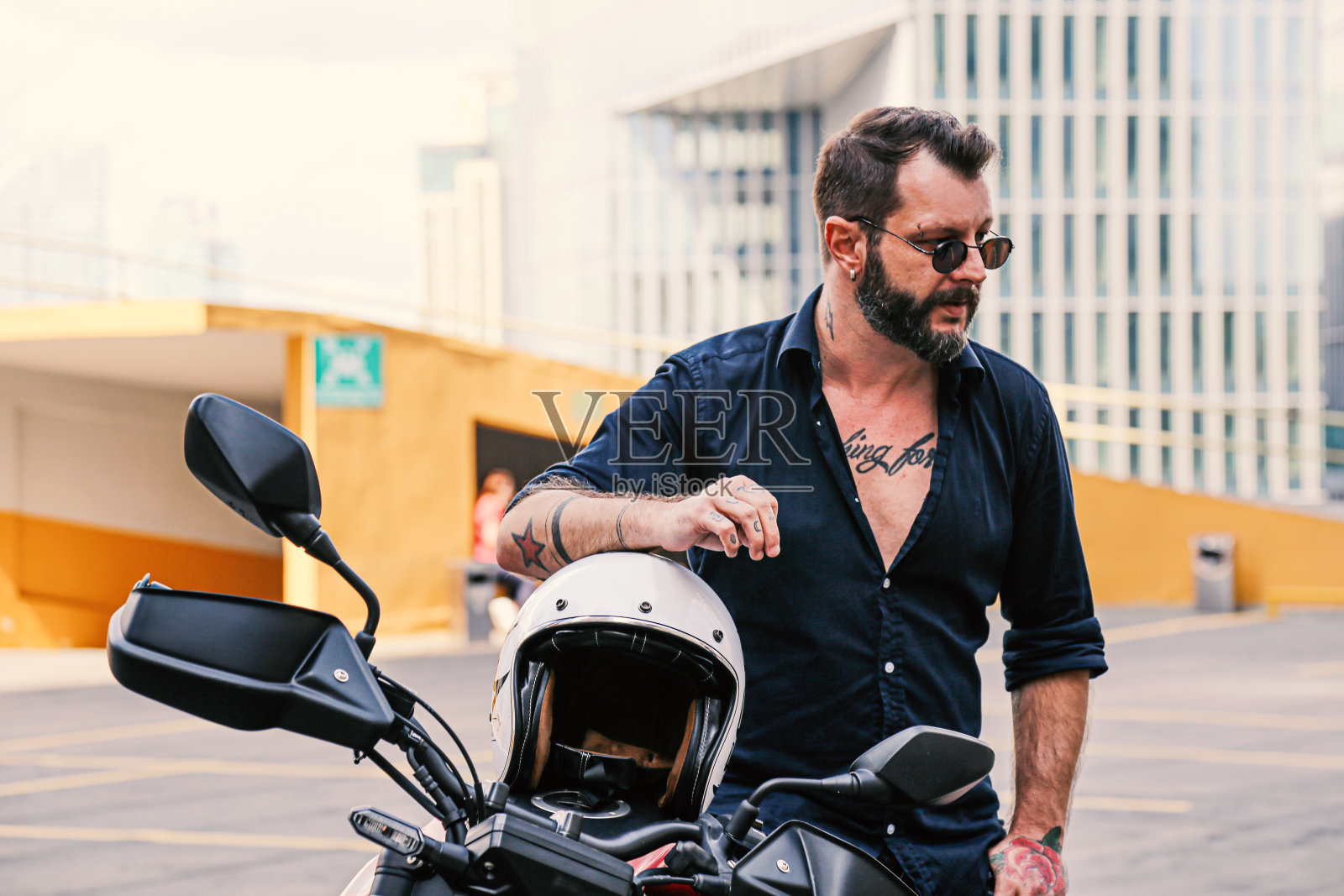 时髦的男人在他的摩托车上摆姿势照片摄影图片