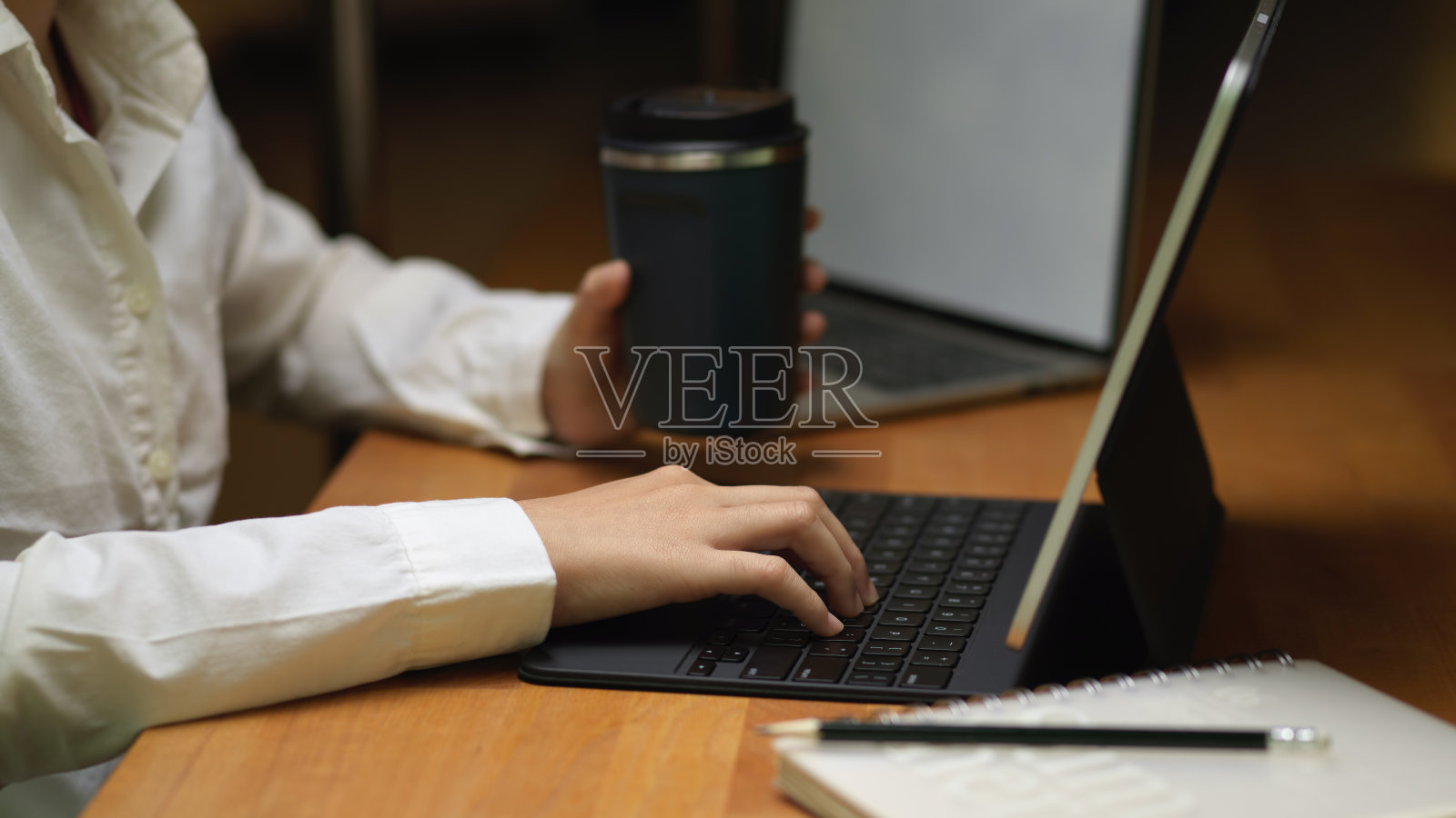 女性在木桌上拿着饮料和平板工作照片摄影图片