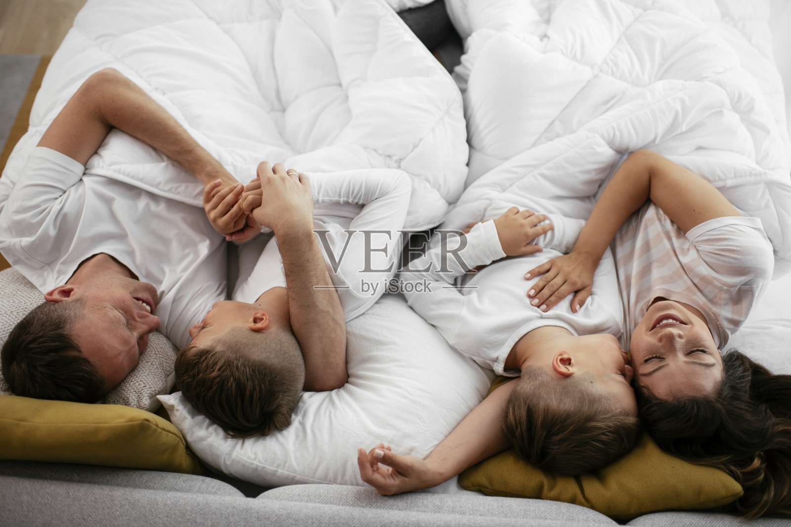 快乐的父母,儿子在床上休息。照片摄影图片