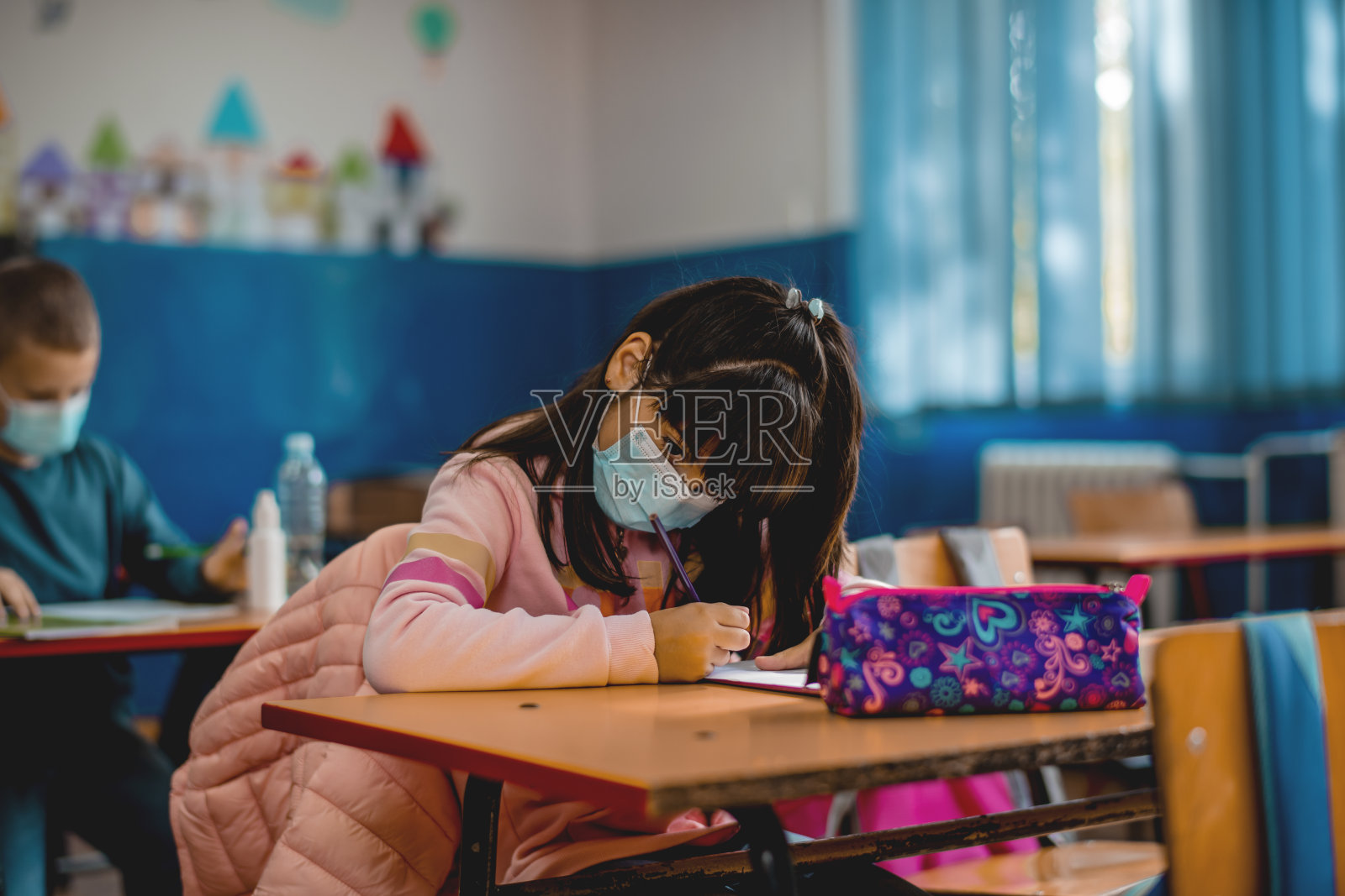 小学生在教室里戴着防护口罩。教育在流行。照片摄影图片