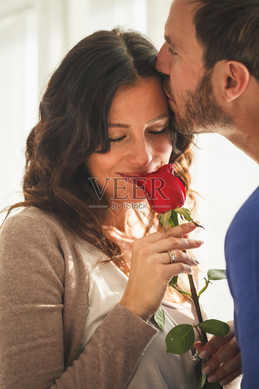 一名男子在送给妻子一朵红玫瑰后亲吻她照片摄影图片