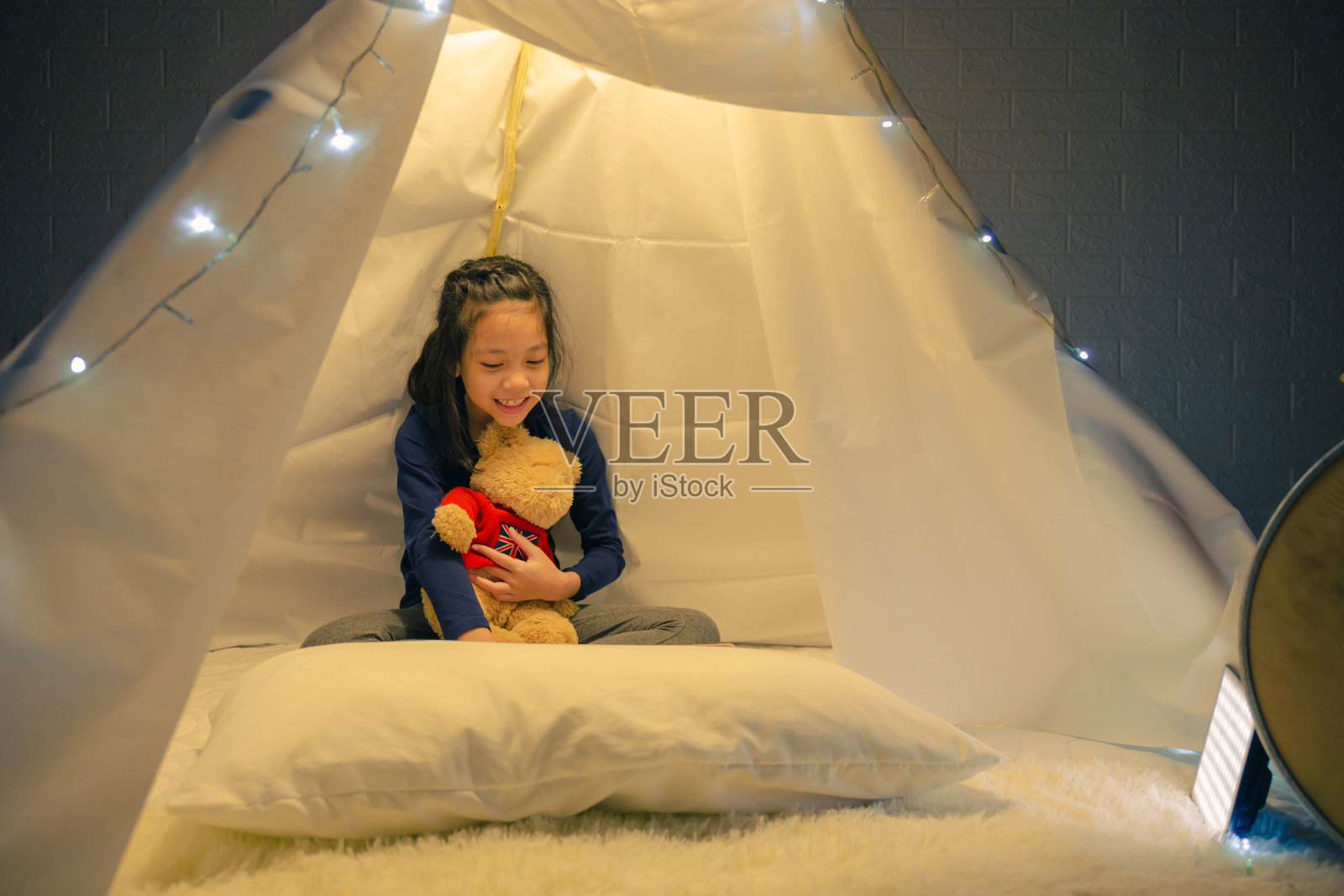 小女孩在帐篷里看书,快乐的孩子在家里玩,有趣可爱的孩子在儿童房玩得很开心。照片摄影图片