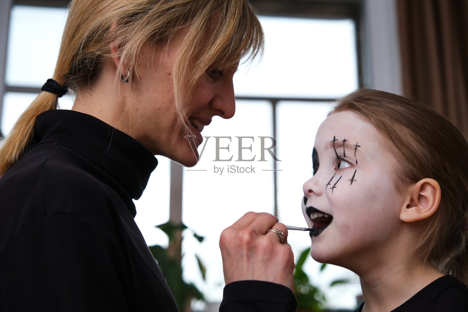 妈妈在帮高加索女儿在室内化妆照片摄影图片