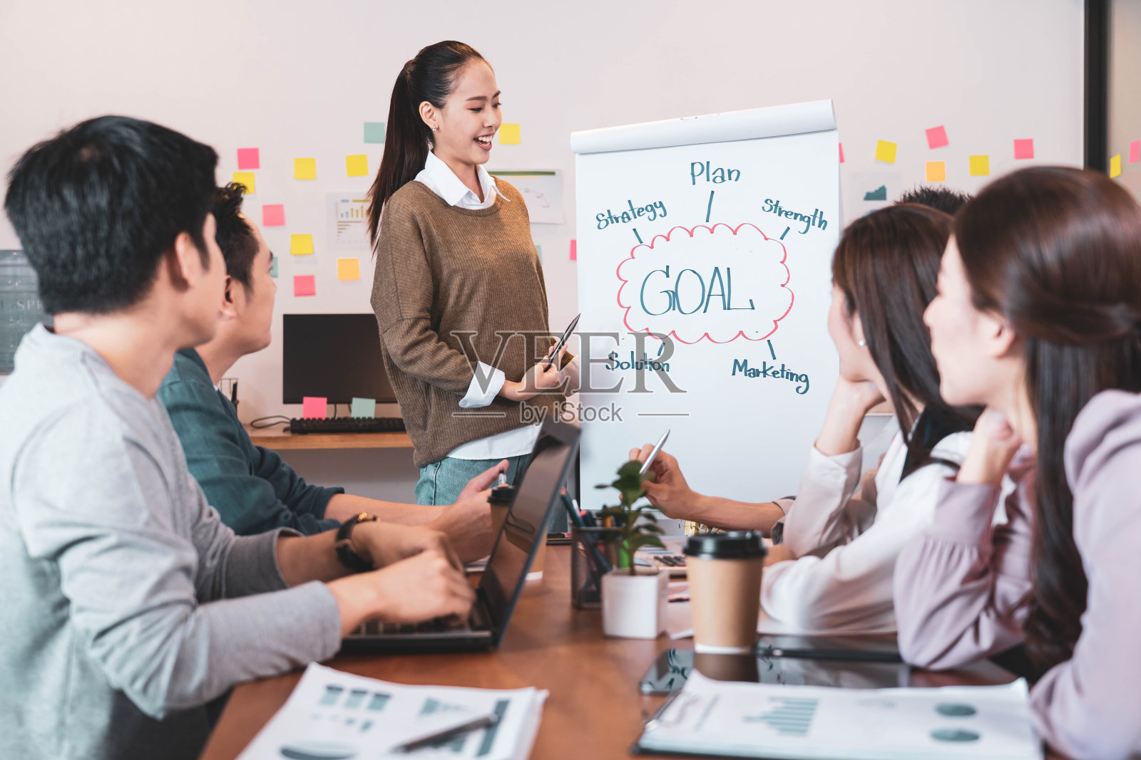 年轻聪明的亚洲商业女性领导者在一个非正式会议上与她的团队同事在现代设计办公室介绍销售策略计划和数据或项目目标时间表的预测照片摄影图片