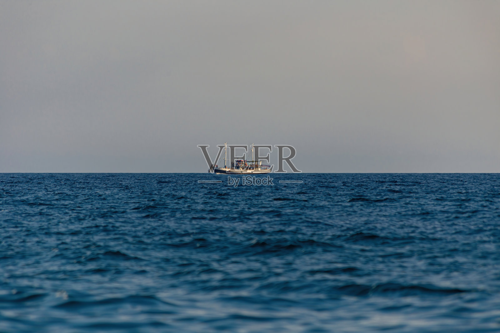 海岸边有一艘船在远处航行。照片摄影图片