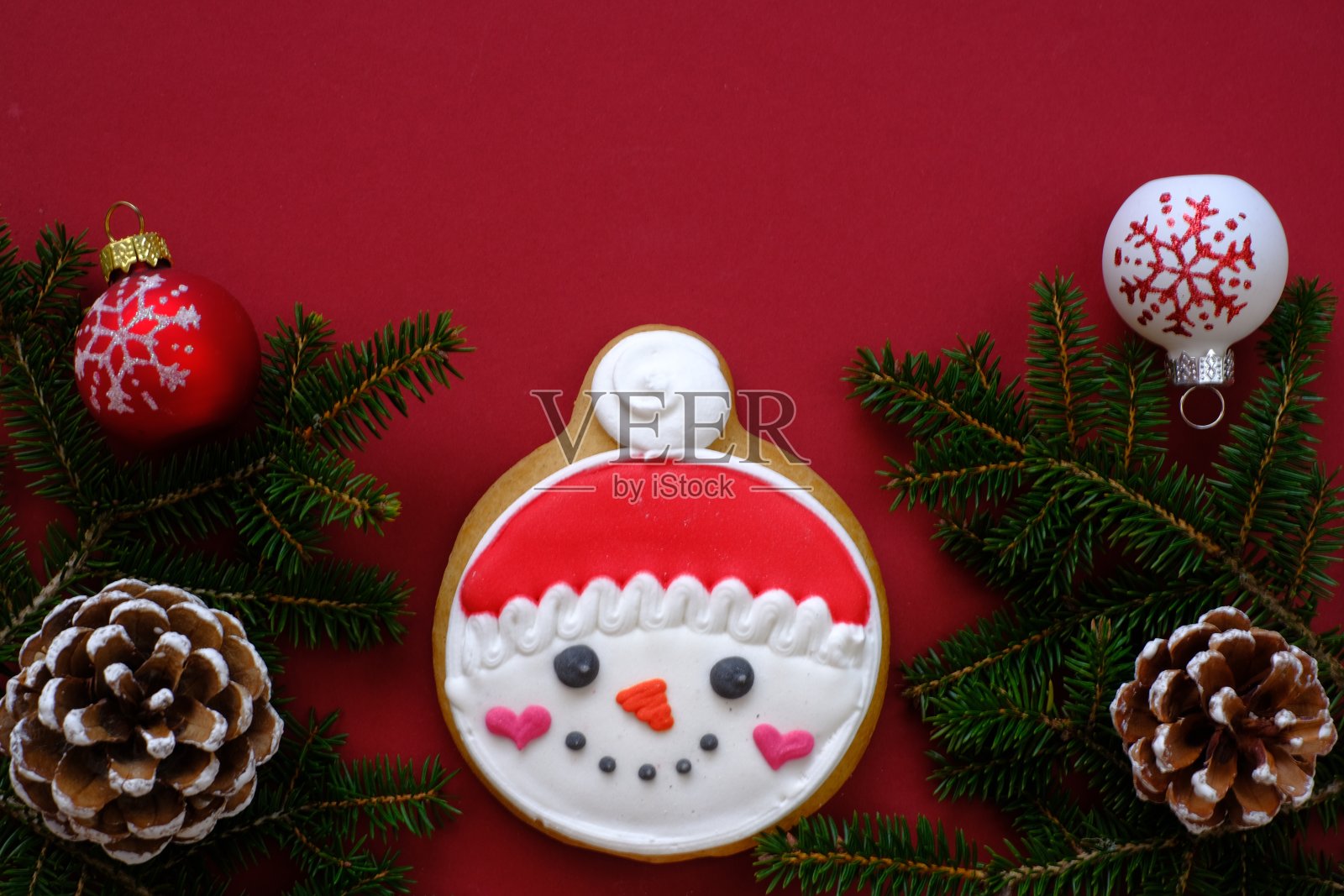 圣诞节和新年假期。圣诞老人的圣诞姜饼饼干与冷杉树枝和锥形,圣诞球在明亮的勃艮第背景。寒假糖果。照片摄影图片