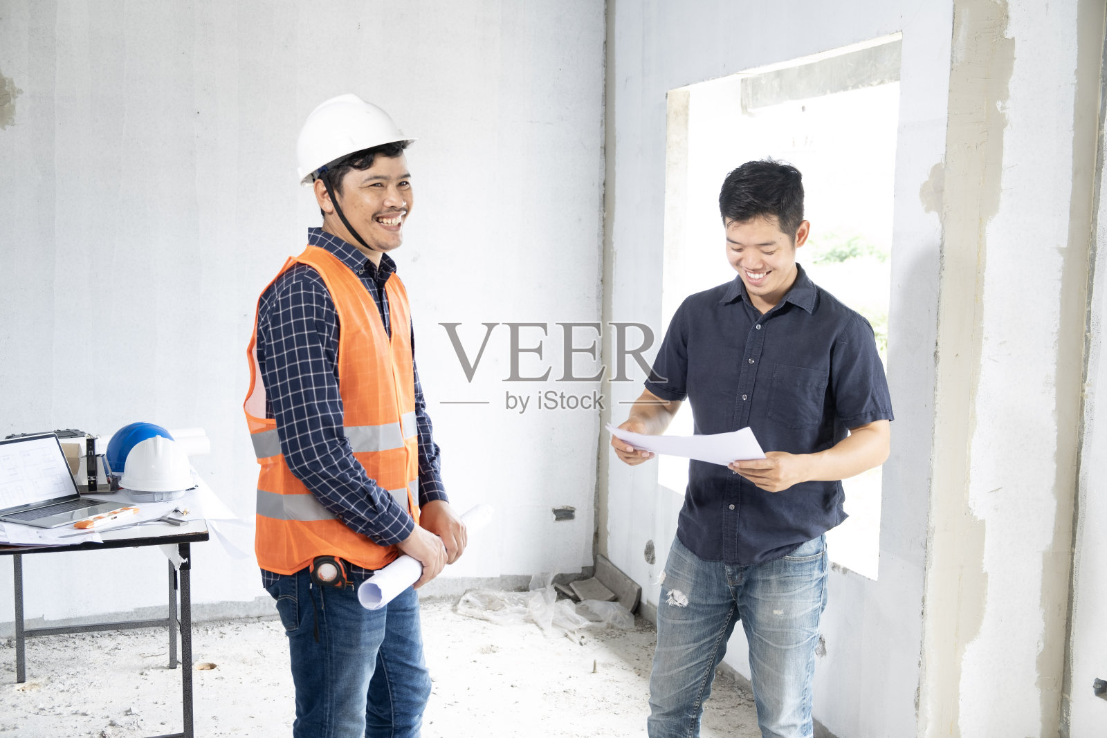 年轻的亚洲人与工头检查房屋建筑,他交叉双臂寻找施工检查房屋建筑现场与客户与新常态冠状病毒照片摄影图片