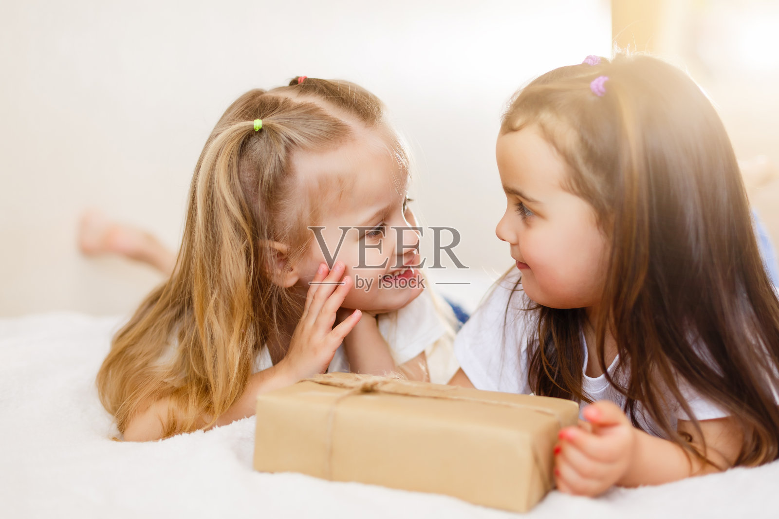 两个小女孩姐妹给孩子女孩打开礼物礼盒照片摄影图片