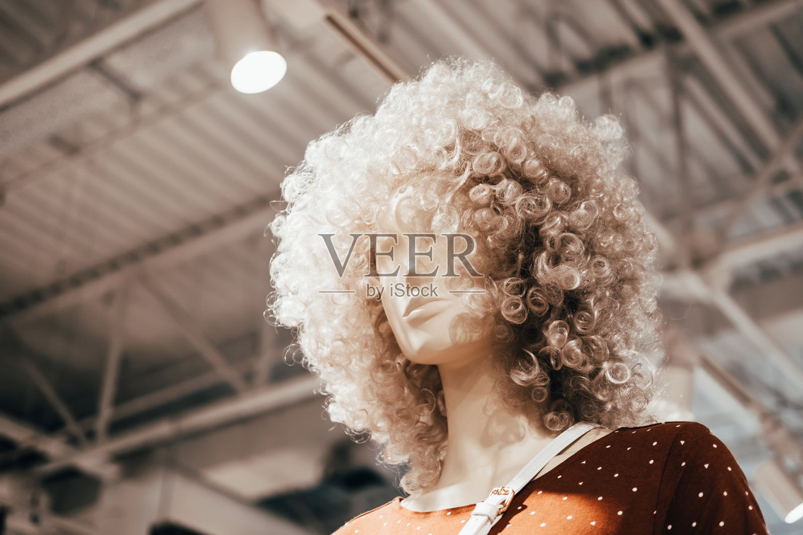 戴着卷曲假发的人体模型站在服装店里。购物、时尚和广告背景照片摄影图片