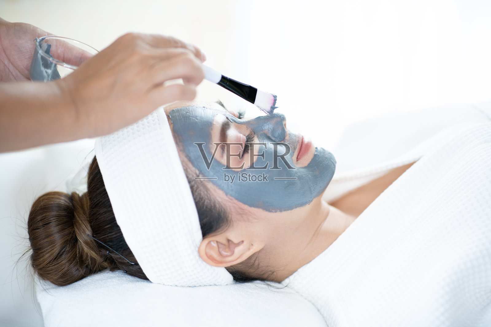 面部皮肤护理。一名亚洲妇女在水疗沙龙里用面具蒙面。有美容spa面膜的女人照片摄影图片