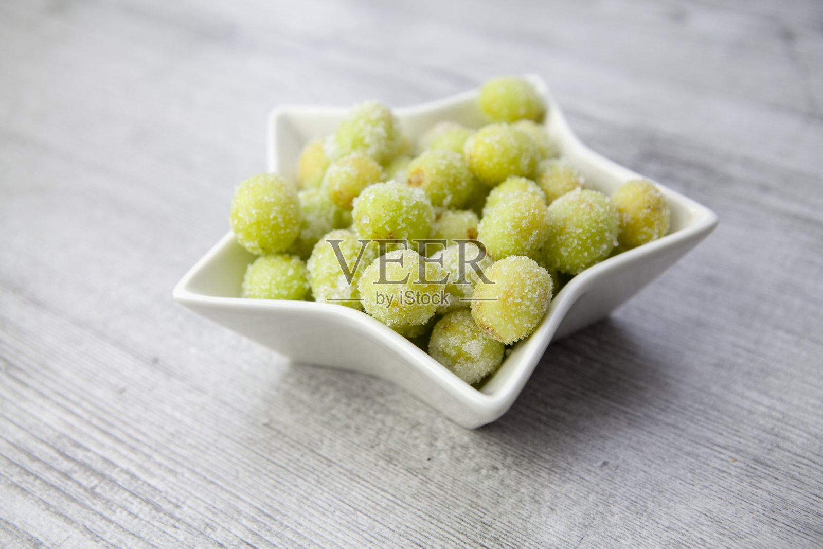 酸糖葡萄在星形碗在木头表面照片摄影图片