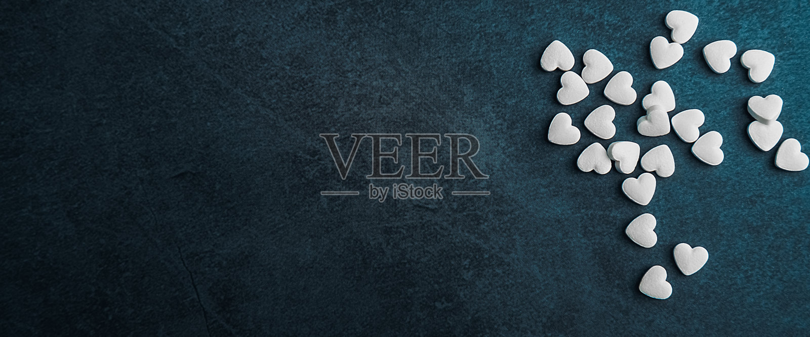 蓝色背景上的心形白色药丸。照片摄影图片