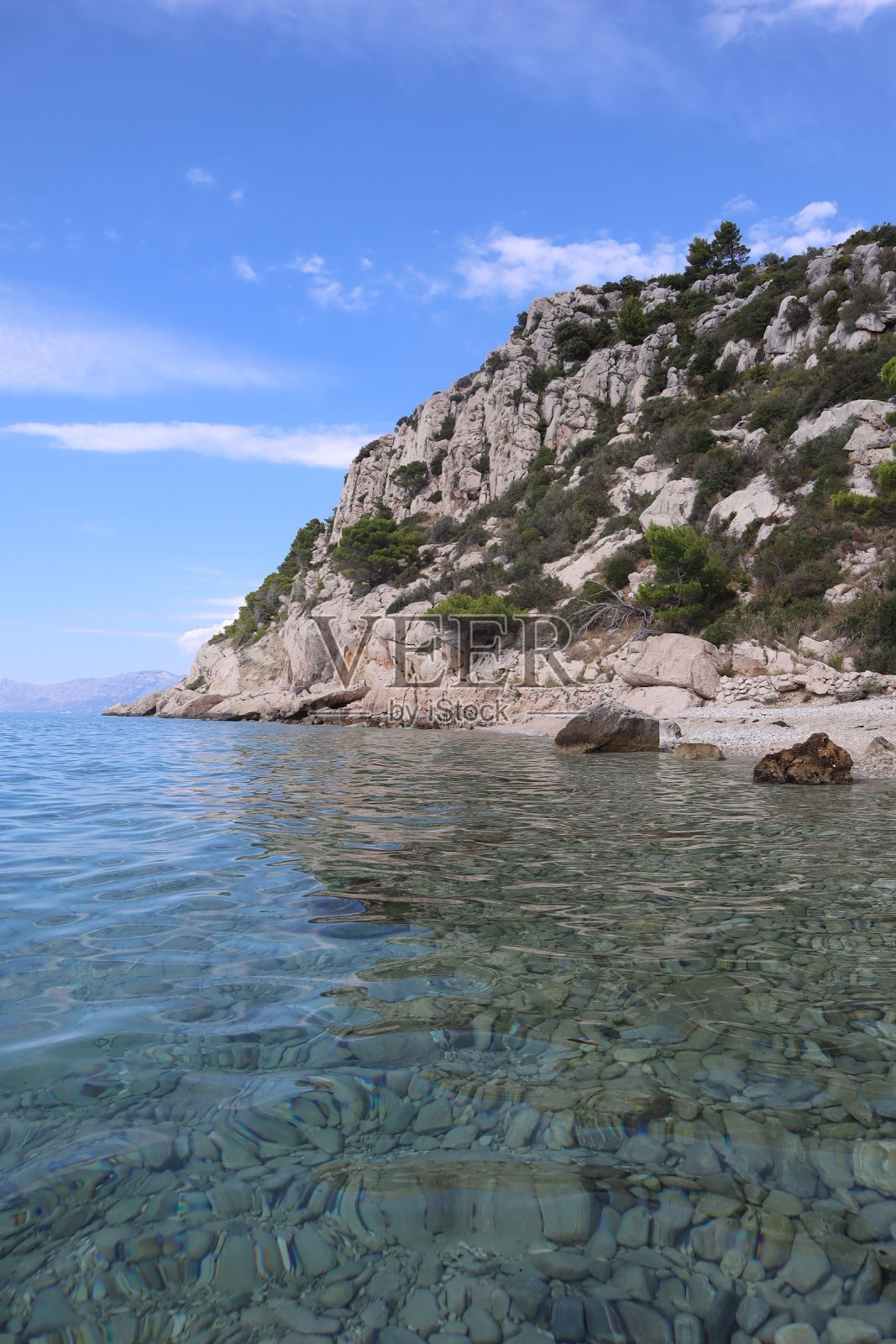 在一个阳光明媚的夏日,克罗地亚海岸的海滩上,清澈的大海和岩石照片摄影图片
