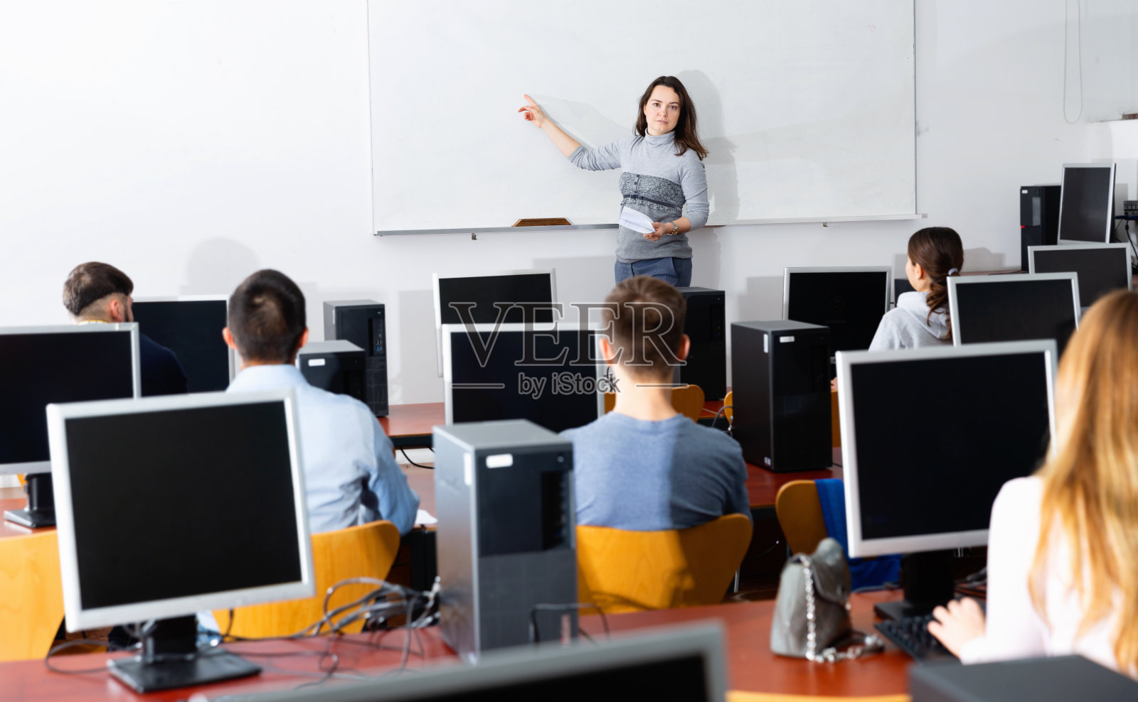 年轻的女教练在计算机课上给成年听众做演讲照片摄影图片
