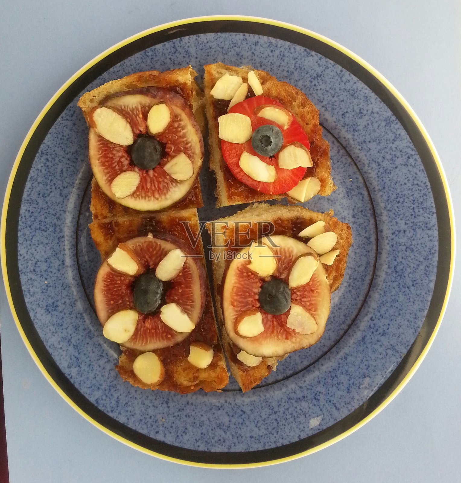 一个蓝色盘子上的无花果和草莓三明治的特写照片摄影图片