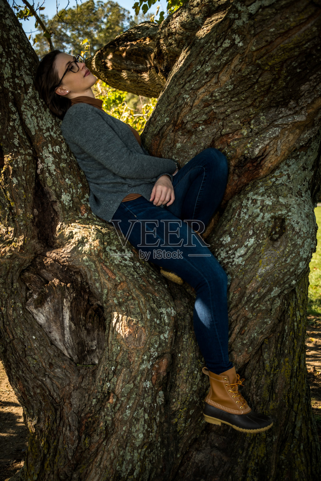 一个年轻女子倚靠在树上照片摄影图片