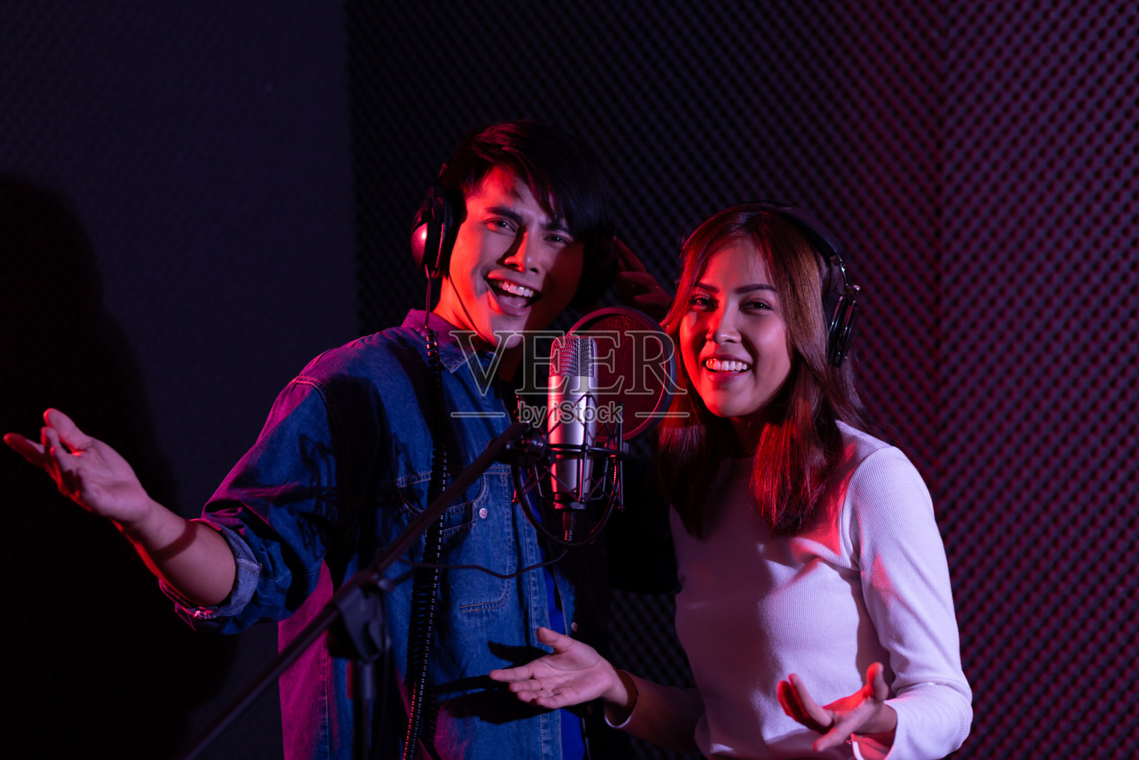 亚洲年轻女子和男子的肖像,艺术家在录音室录制歌曲时对着麦克风唱歌照片摄影图片