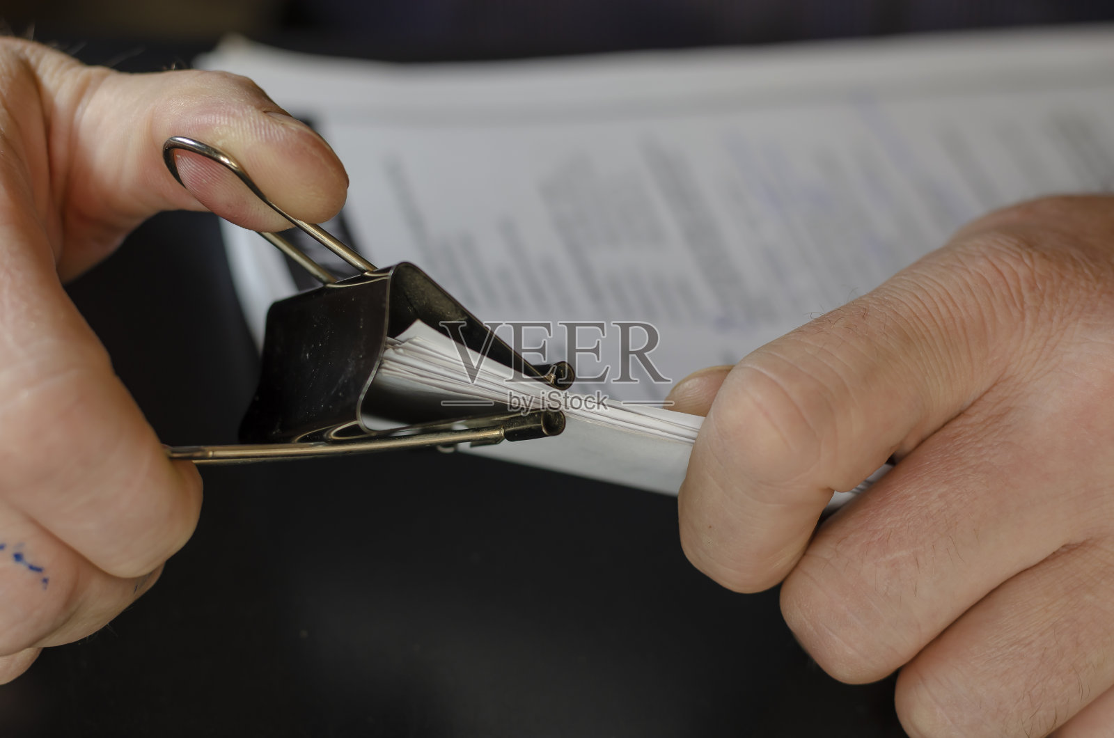 男性的手拿着纸与黑色金属夹的特写。照片摄影图片