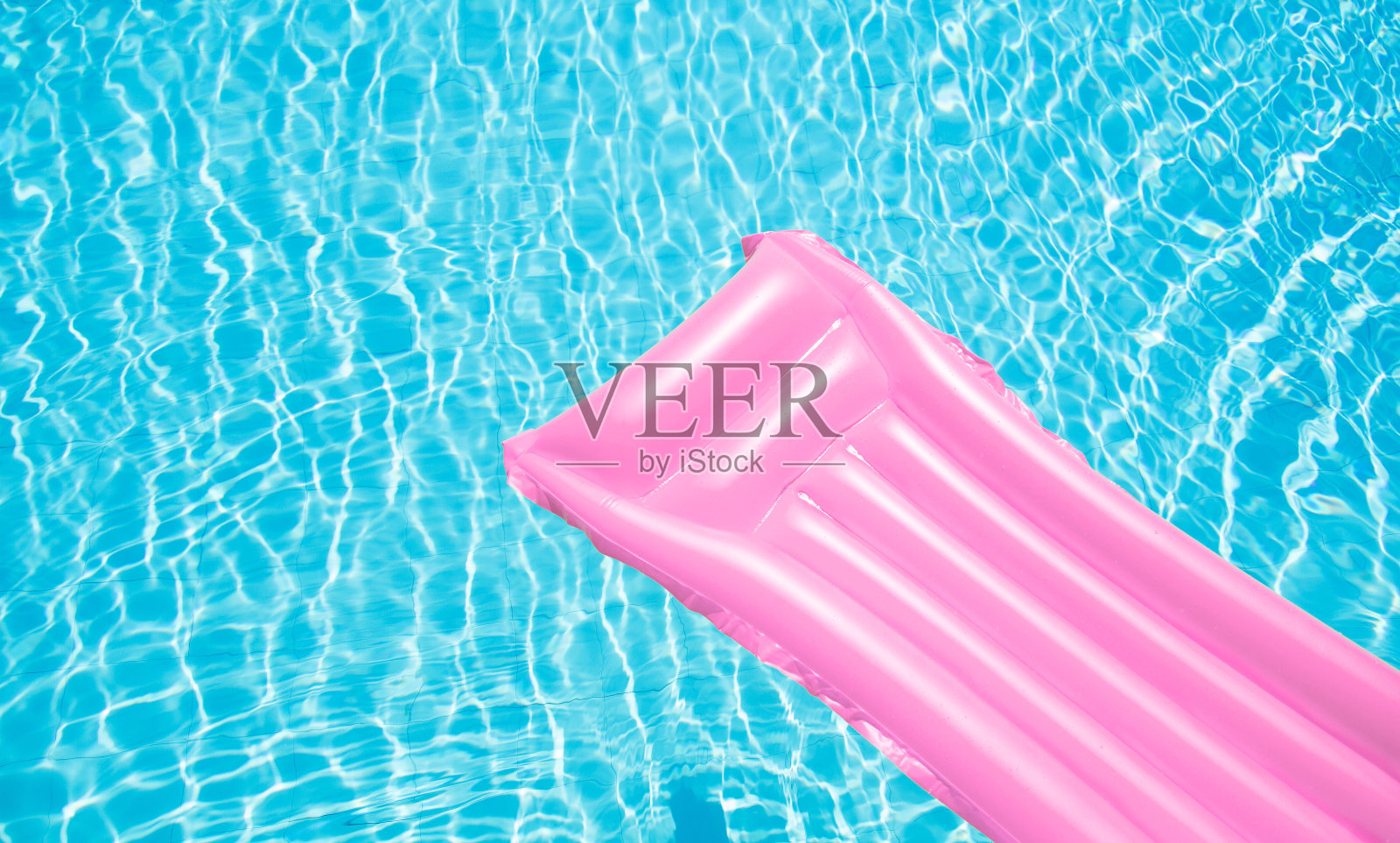 海滩暑假背景。游泳池水上的充气床垫。泳池边的粉色气垫和夏季配饰。俯视图和复制空间。横幅照片摄影图片